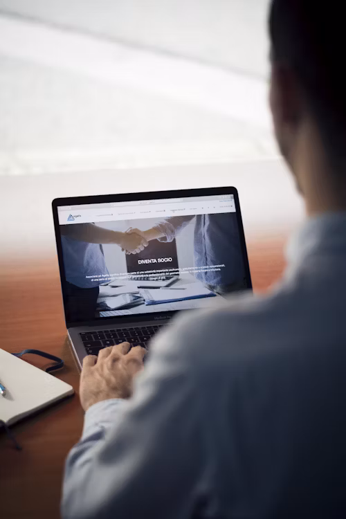 A man reading a website on a laptop at a desk